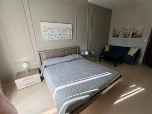 a bedroom with a bed and a chair in it at Ta'Roza Modern Apartment with Balcony & Distant Sea Views - Xaghra Gozo in Xagħra