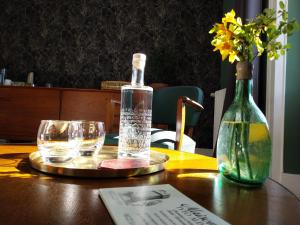 a bottle and glasses on a table with a vase at Maison Tyto Alba in Saint-Victurnien