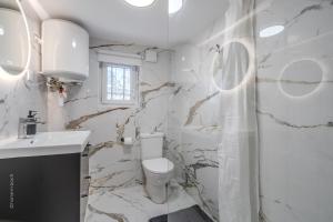 a white bathroom with a toilet and a sink at Studio élégant en RDC, confort et simplicité in Vaires-sur-Marne
