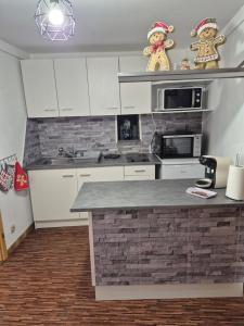 a kitchen with white cabinets and a brick wall at Le repaire des Manalas in Ingersheim