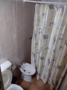 a bathroom with a toilet and a shower curtain at Hospedaje Andacollo in Balde del Rosario