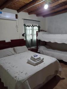 a bedroom with two beds with white sheets and a window at Hospedaje Andacollo in Balde del Rosario