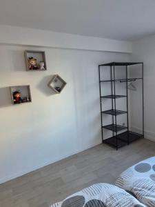 a room with a white wall with two pictures and a shelf at Le repaire des Manalas in Ingersheim +1 photo