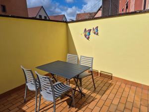 a patio with a table and chairs on a yellow wall at Le repaire des Manalas in Ingersheim