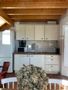 a kitchen with white cabinets and a table with a plant at Marvão Country Houses - Queixos II in Santo António das Areias