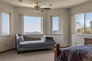 a bedroom with a ceiling fan and a couch and windows at Hidden Views Cabin in Twain Harte