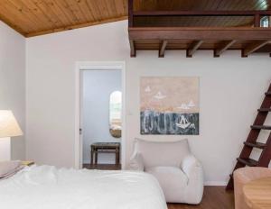 a bedroom with a white bed and a chair at Sanctuary Spaces - Sunset Bungalow 101 in Byron Bay