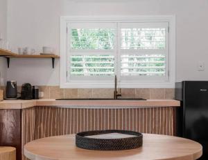 a kitchen with a round table with a window at Sanctuary Spaces - Sunset Bungalow 101 in Byron Bay +2 photos