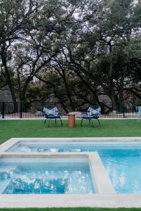 a swimming pool with two lawn chairs and trees at Camp Cold Springs in Concan