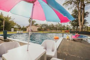 a pool with an umbrella and a child in a raft at Gaúcha Pesca, Lazer e Pousada in Guaíra