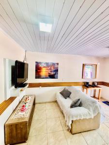 a living room with a bed and a tv at Refúgio da Serra - Apto Completo a 3 minutos do centro de Canela in Canela