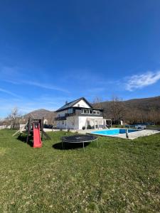 a house with a playground in the yard at Lika Relax and Party House with sauna, jacuzzi and outdoor heated swimming pool in Lovinac