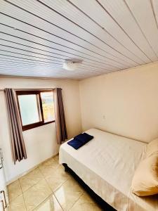 a small bedroom with a bed and a window at Refúgio da Serra - Apto Completo a 3 minutos do centro de Canela in Canela