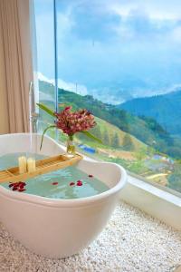 a bath tub with a vase of flowers in a window at Sapa Lumia Hotel in Sapa