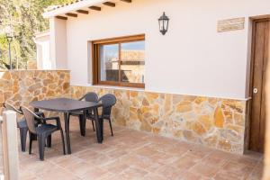 a patio with a table and chairs and a stone wall at Apartamentos 7 Puentes Sierra Cazorla Las 5 casas iguales in Burunchel