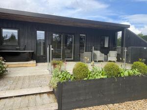 a black house with a deck and chairs on it at Mackie lodge in Luss