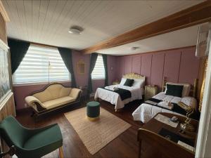 a bedroom with two beds and a couch and a chair at Gite de la Baie Hatée in Bic
