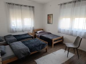 a bedroom with three beds and a chair and windows at MORLAK - Guest House - Restaurant - Gated parking in Polača