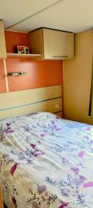 a bedroom with a bed with a floral comforter at Mobile Home privé dans camping n 69 in Port-Bail-sur-Mer