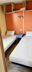 a room with two beds and a blue table at Mobile Home privé dans camping n 69 in Port-Bail-sur-Mer
