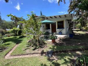 a white house with a green umbrella in a yard at Don Lioni in El Valle de Antón