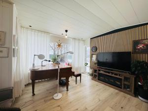 a living room with a piano and a flat screen tv at Langafit Guest house in Garðabær