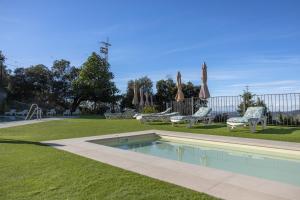 a swimming pool in a yard with chairs and umbrellas at Apartamentos 7 puentes sierra Cazorla Los 2 Dúplex in Burunchel