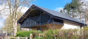 a house with a black roof in the woods at The Coach House in Torpoint +8 photos