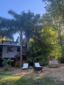 a house with two chairs and a palm tree at Cabañas Allende Delta in Tigre +6 photos