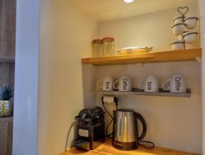 a kitchen with a coffee pot and cups on a shelf at Beachfront Studio in Marigot in Marigot