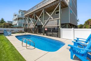 a swimming pool with two blue chairs and a building at Crabcake Village OBX in Salvo