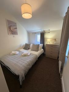 a bedroom with a bed with two towels on it at Elegant Flat in Ealing in Greenford +20 photos
