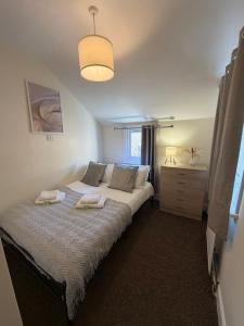 a bedroom with a bed with two towels on it at Elegant Flat in Ealing in Greenford