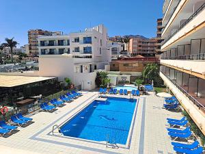 an outdoor swimming pool with blue chairs and a building at Apartamentos Buensol in Torremolinos
