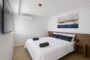 a white bedroom with a large white bed with blue pillows at Prime Suites Valencia in Valencia