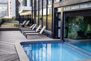 a pool with lounge chairs next to a building at Onyx Studio Apartment in Cape Town