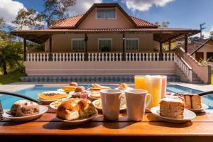 a table with breakfast foods and drinks on it at Pousada Chalés Villa Pinhal in Santo Antônio do Pinhal