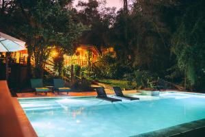 a swimming pool with two chairs and an umbrella at Tacuapí Lodge in Aristóbulo del Valle