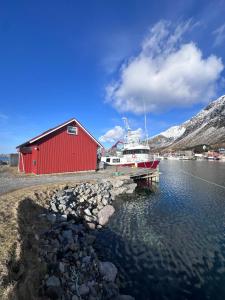 a boat is docked next to a red building at Lysbøen Bua in Ramberg