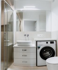 a bathroom with a washing machine and a sink at Apartament Różany 2 in Busko-Zdrój