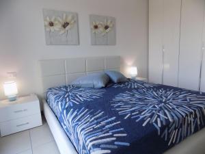 a bedroom with a blue and white bed and two lamps at Hotel Residence Sole in Fontanafredda