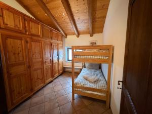 a bedroom with a bunk bed in a room with wooden cabinets at Mountain Chalet Ca' dal Ghiru by Villa Bernardino Galliari in Sagliano Micca