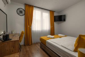 a bedroom with a bed and a desk and a window at Hotel Domestika in Skopje