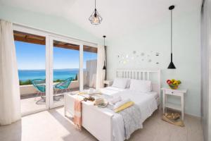 a white bedroom with a bed and a view of the ocean at Villa Damian in Barbati +9 photos
