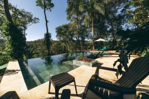 a swimming pool with two chairs and a bench at Tacuapí Lodge in Aristóbulo del Valle