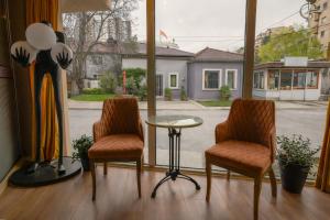two chairs and a table in a room with a window at Hotel Domestika in Skopje