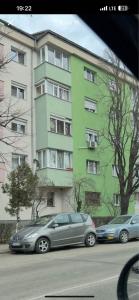 two cars parked in front of a green building at city apartament in Oradea