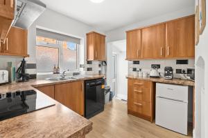 a kitchen with wooden cabinets and black appliances at 5-Bed Family & Group Stay Near Cricket Ground in Worcester