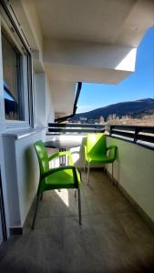 a balcony with two green chairs and a window at My Life 19 - Green Hill in Soko Banja