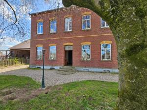 a large brick building with a tree in front of it at Das alte Herrenhaus auf dem Bio-Bauernhof in Kevelaer